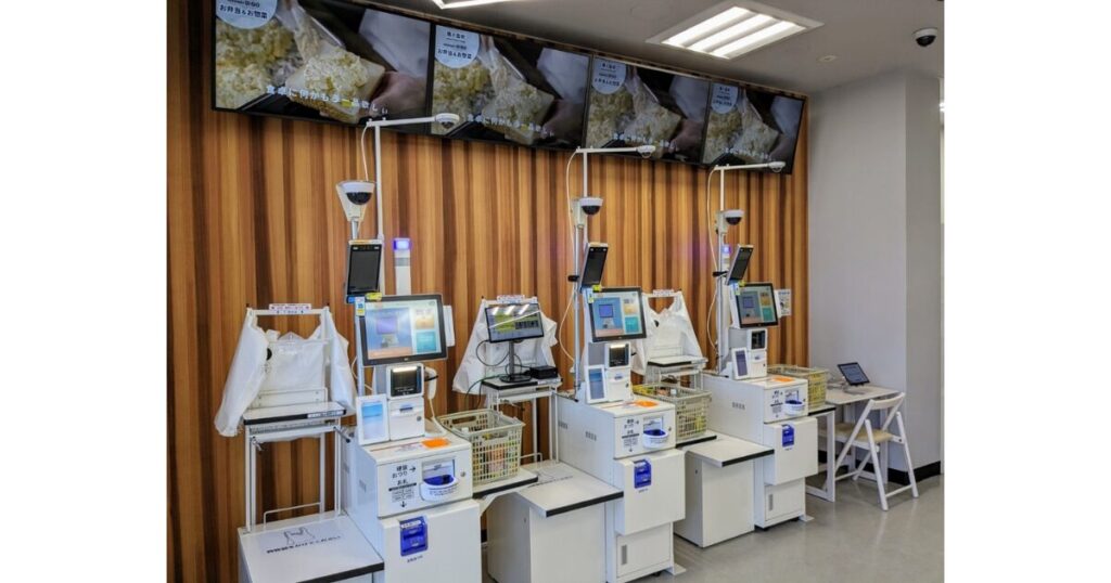 木目調の壁の前に複数台並んで設置されている、店舗省人化のための最新型コンビニセルフレジ端末。