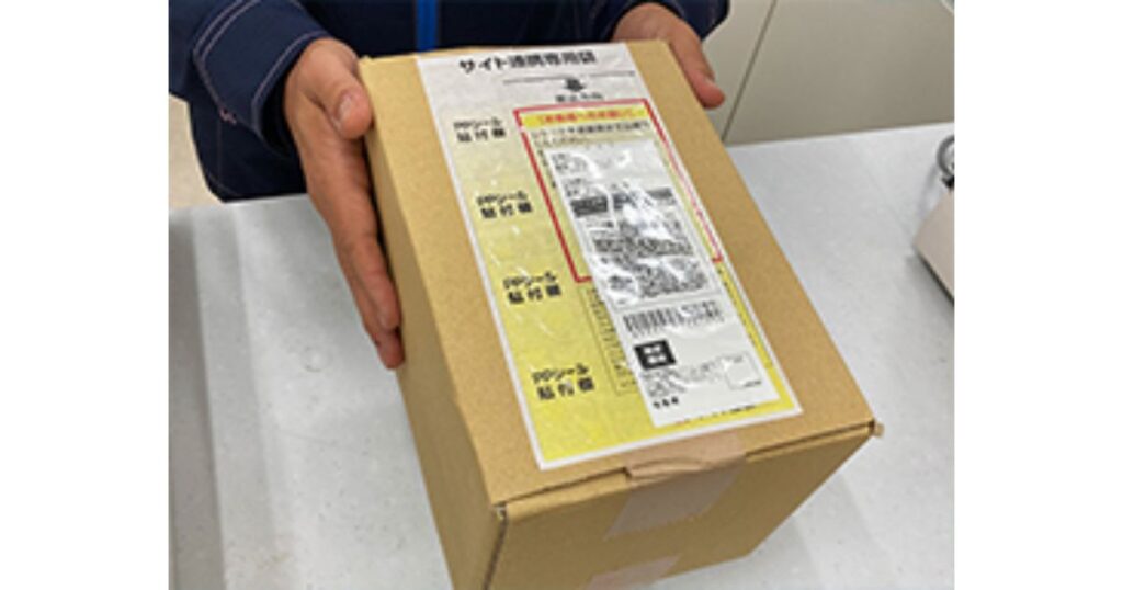 フリマアプリ等の発送用として、サイト連携専用袋と送り状が表面に貼り付けられた段ボール箱。